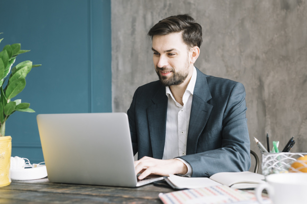positive-businessman-using-laptop_23-2147800028